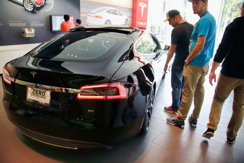 In this Saturday, Jan. 3, 2015 photo, people check out the Tesla model S at the Tesla...