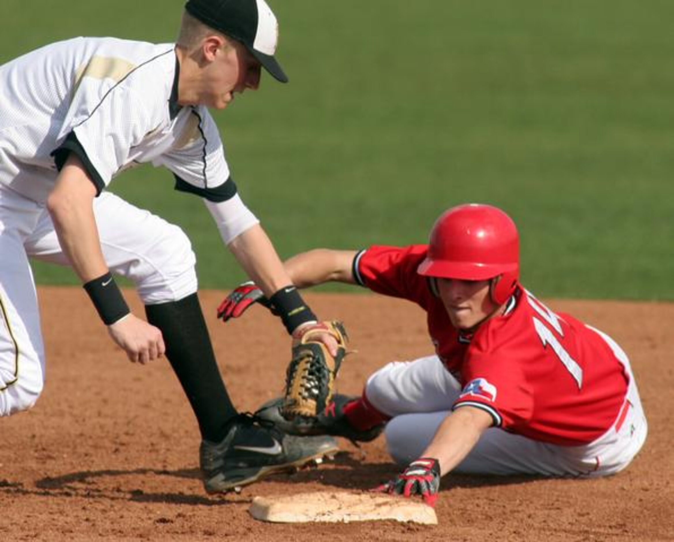 Justin Northwest's Cody Cunningham slides under the tag of Plano East's Jeff Emens (5) tag...