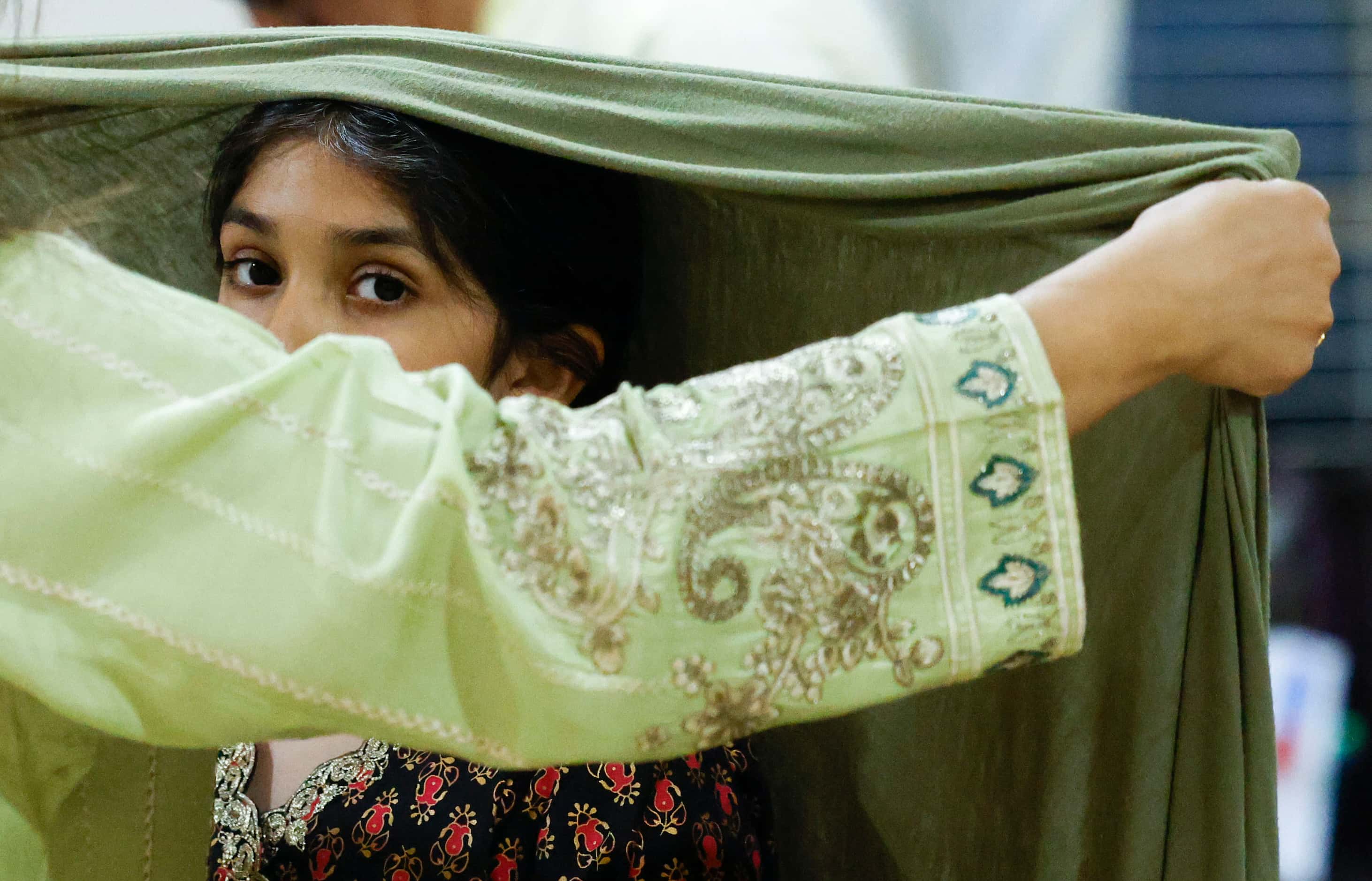 Natasha Butt, helps her daughter, Anaya Choudhry, 8, with her head wrap ahead of Maghrib...