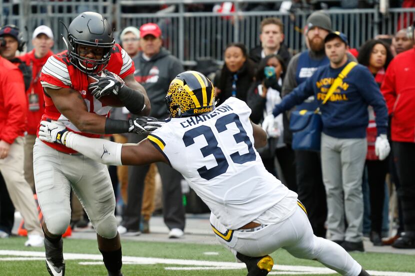 Ohio State running back Mike Weber, left, runs the ball as Michigan defensive end Taco...