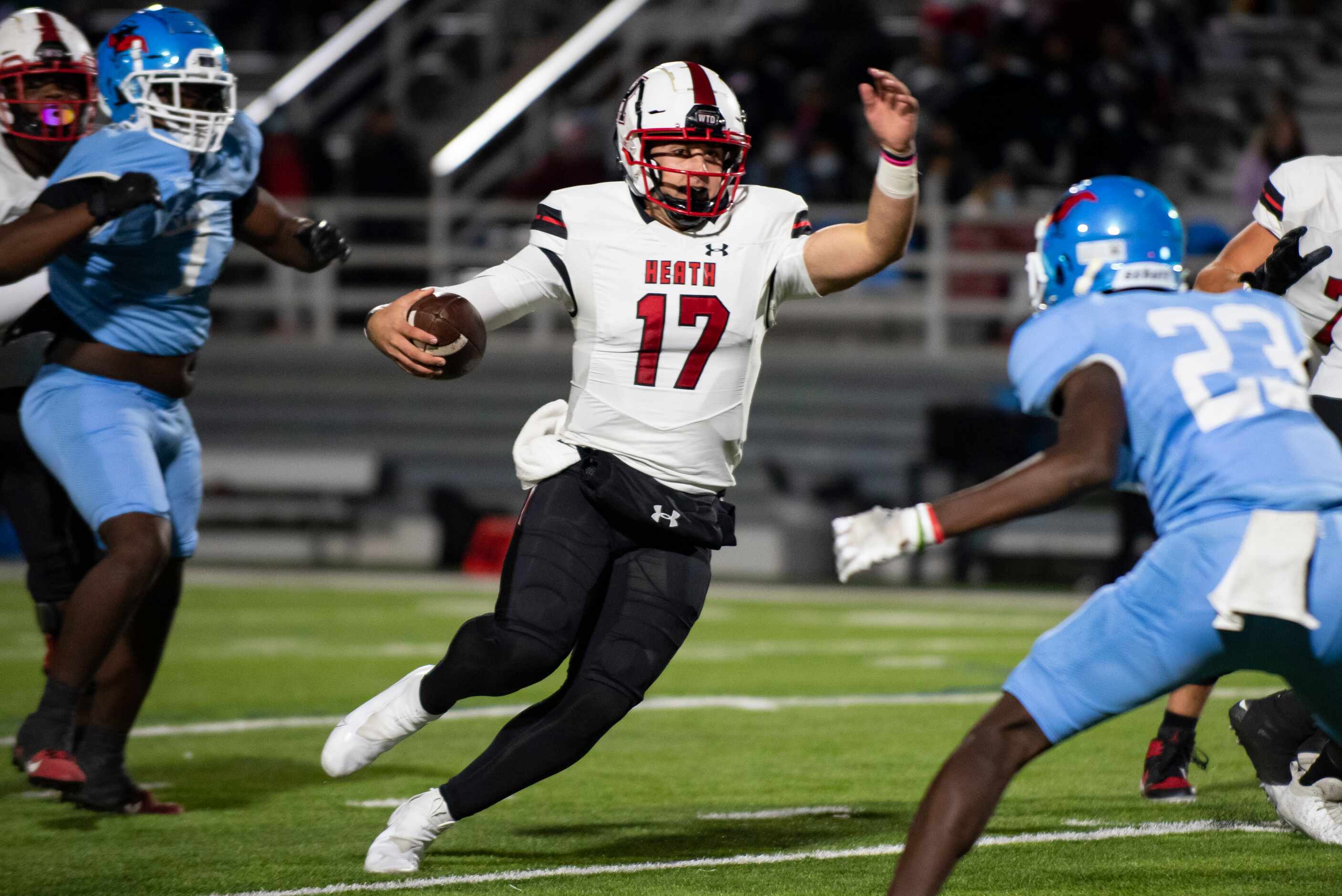 Heath senior Josh Hoover (17) avoids a tackle from Skyline sophomore La’Monya Woods (23)...