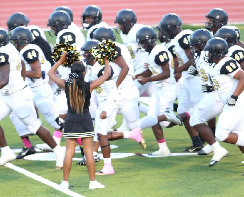 A Golden Bears cheerleader spreads cheer as members of the South Oak Cliff football team hit...