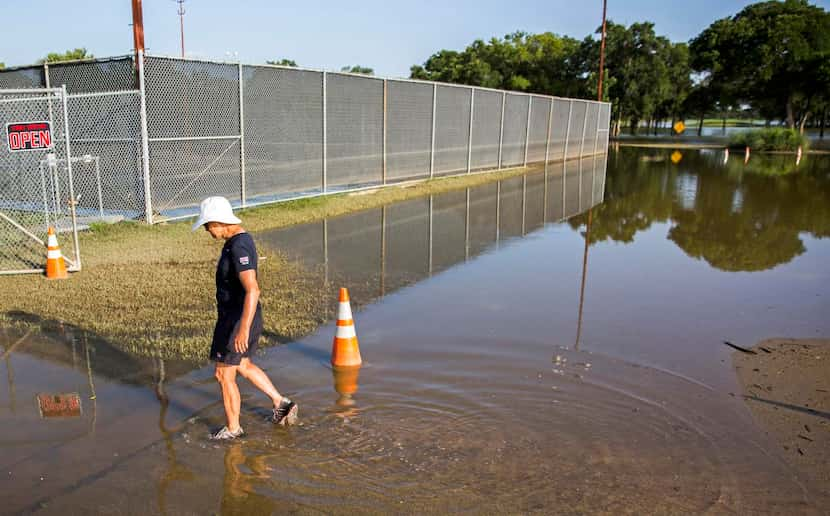 
Andrea Rains, head pro and manager of L.B. Houston Tennis Center, walks through high water...