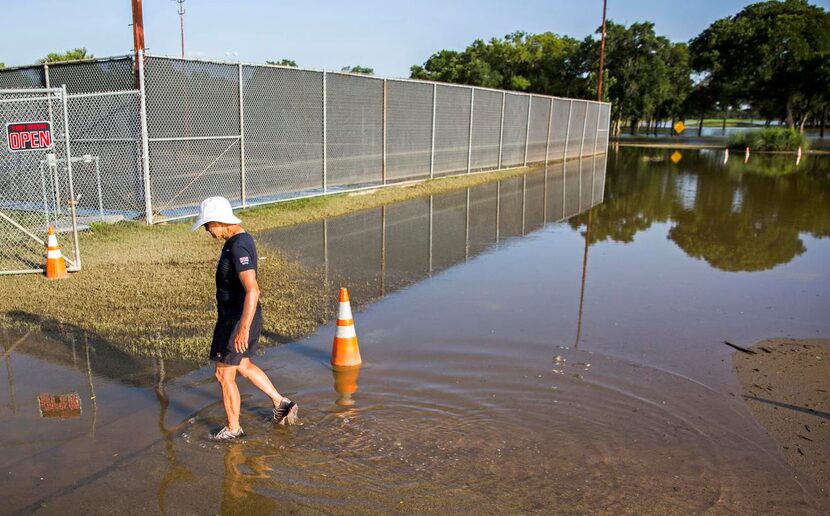 
Andrea Rains, head pro and manager of L.B. Houston Tennis Center, walks through high water...