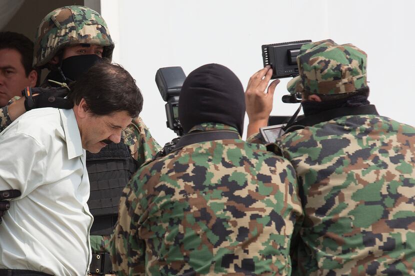 Drug trafficker Joaquin "El Chapo" Guzman is escorted to a helicopter by Mexican security...