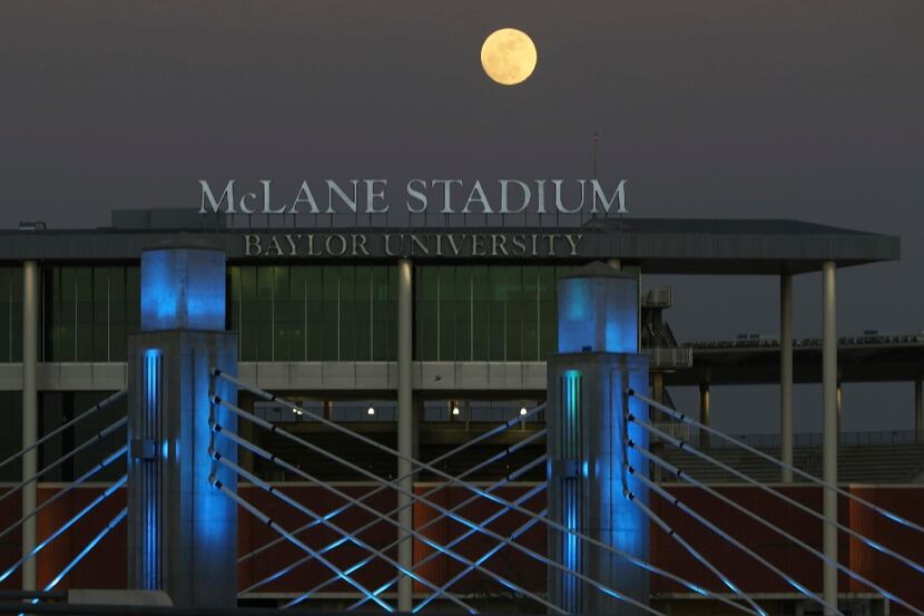 A full moon rises over the Brazos River near Baylor University's McLane Stadium and...