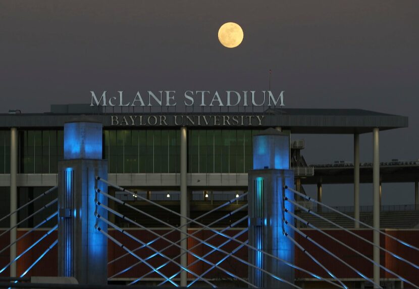 A full moon rises over the Brazos River near Baylor University's McLane Stadium and...