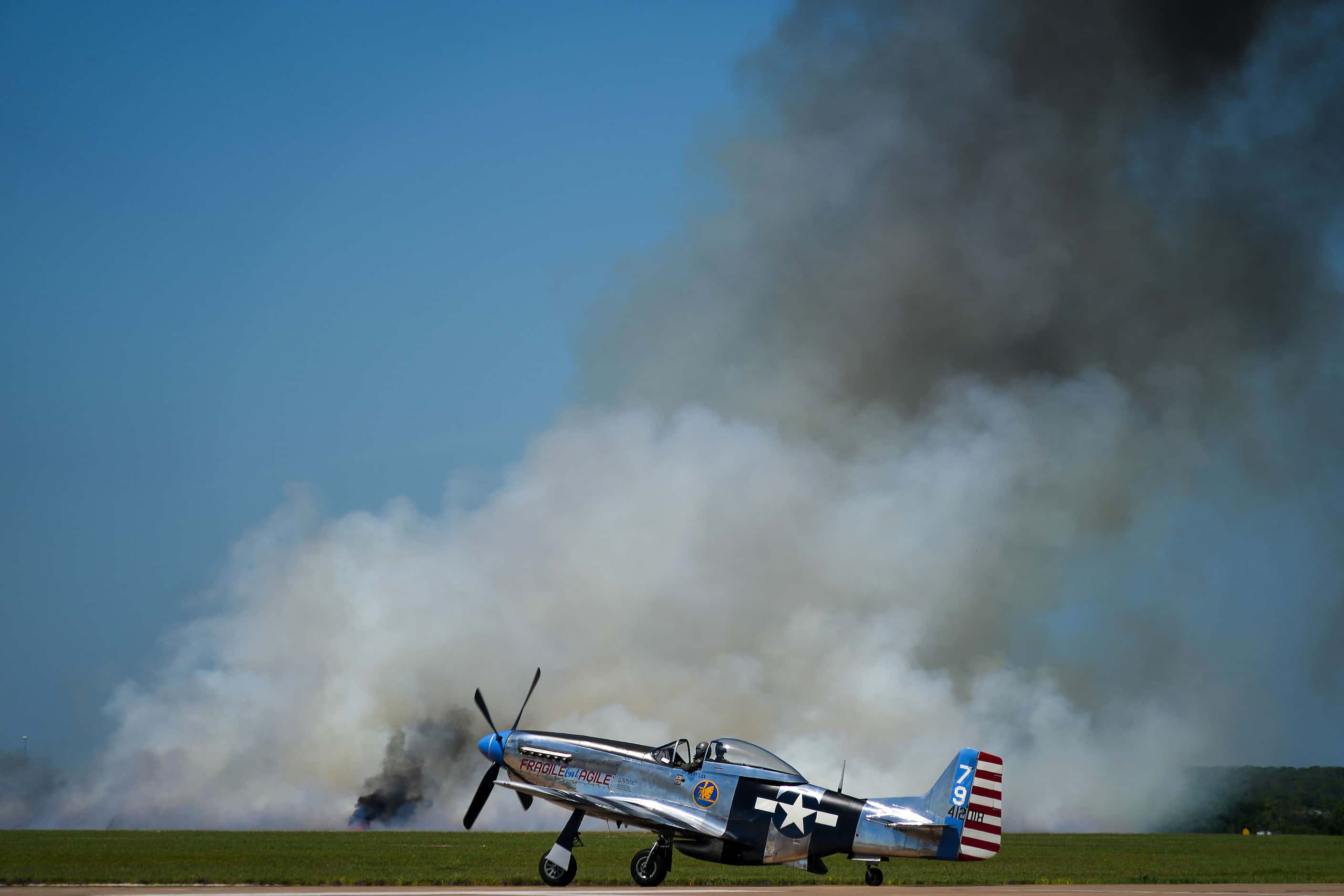 A P-51 taxis to the runway past smoke deployed as part of the show during the Wings Over...