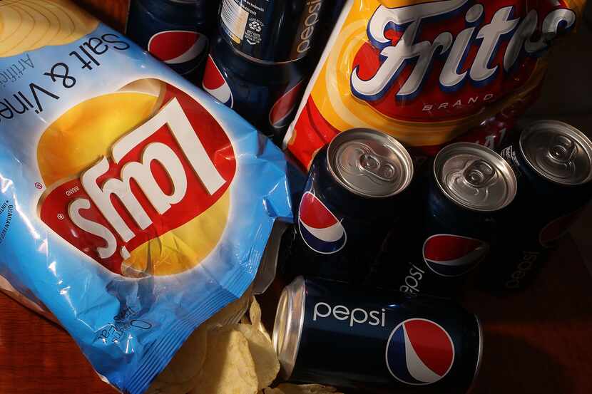 A bag of chips maufactured by PepsiCo's Frito-Lay brand and cans of its Pepsi soda.