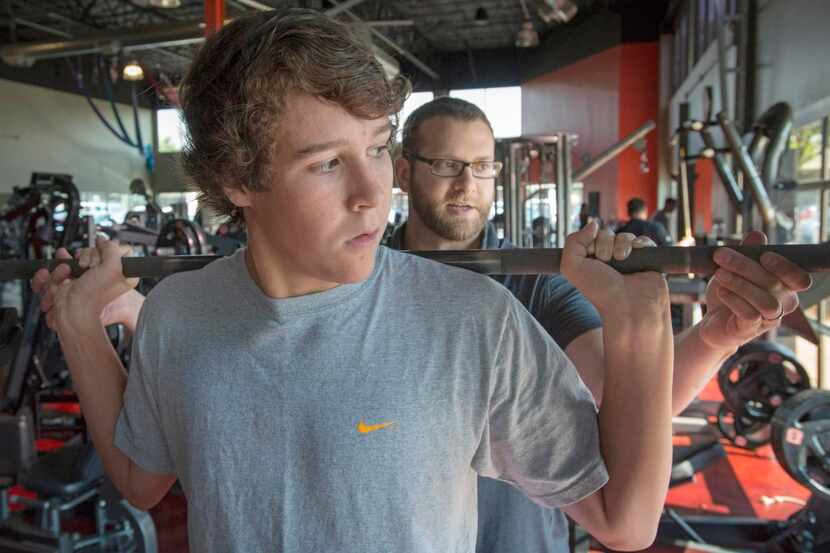 
Patrick Sagui (right) helps Camden Turner with squats during a workout at Sweat gym in...