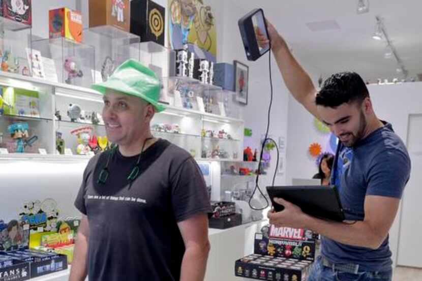 
Victor De Los Angeles (right), owner of Cubo toy store, uses a Sense 3D scanner on coffee...