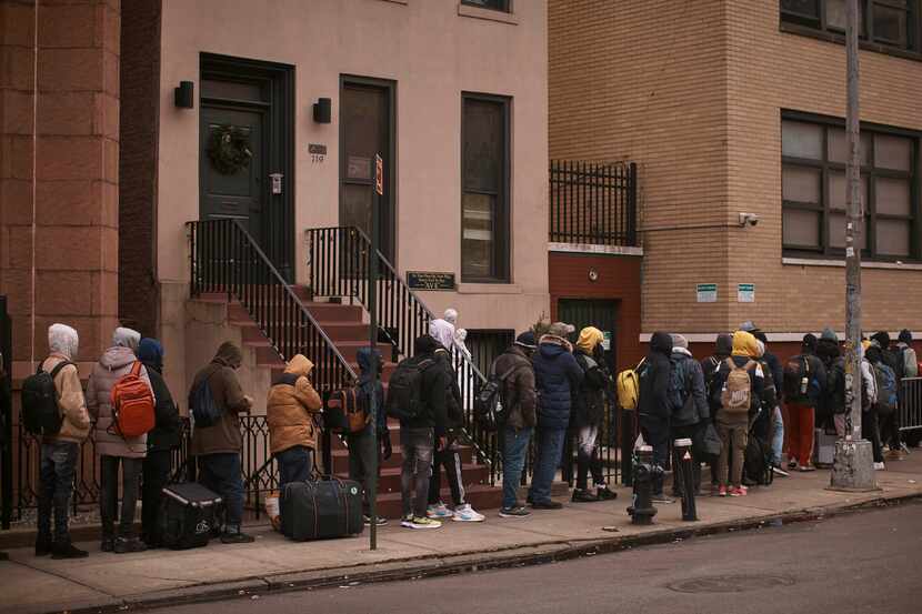Migrants queue in the cold as they look for a shelter outside a migrant assistance center at...