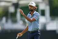 Akshay Bhatia waves after hitting his birdie putt on the 18th green during the first round...