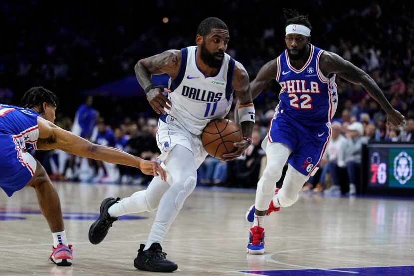 Dallas Mavericks' Kyrie Irving, center, drives against Philadelphia 76ers' Jaden Springer,...