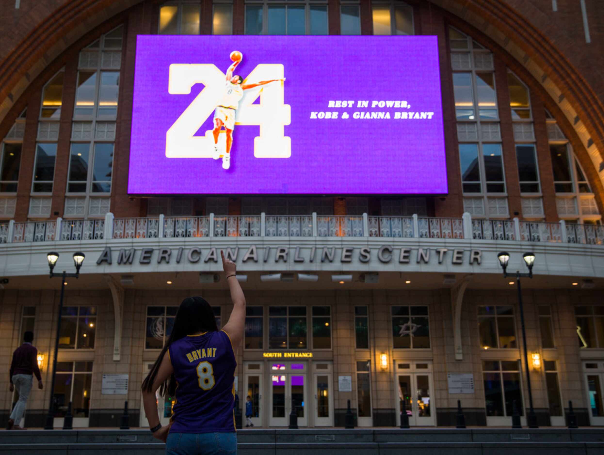 Josefina Martinez points to a large screen displaying a tribute to former Los Angeles Laker...