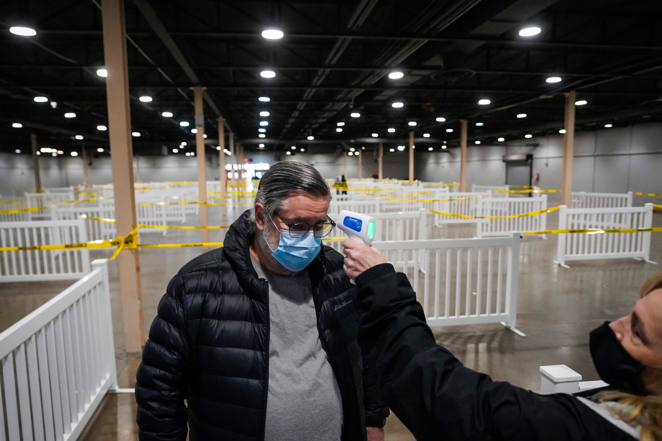 Davis Mosmeyer, 69, has his temperature taken as he enters the building at the front of the...