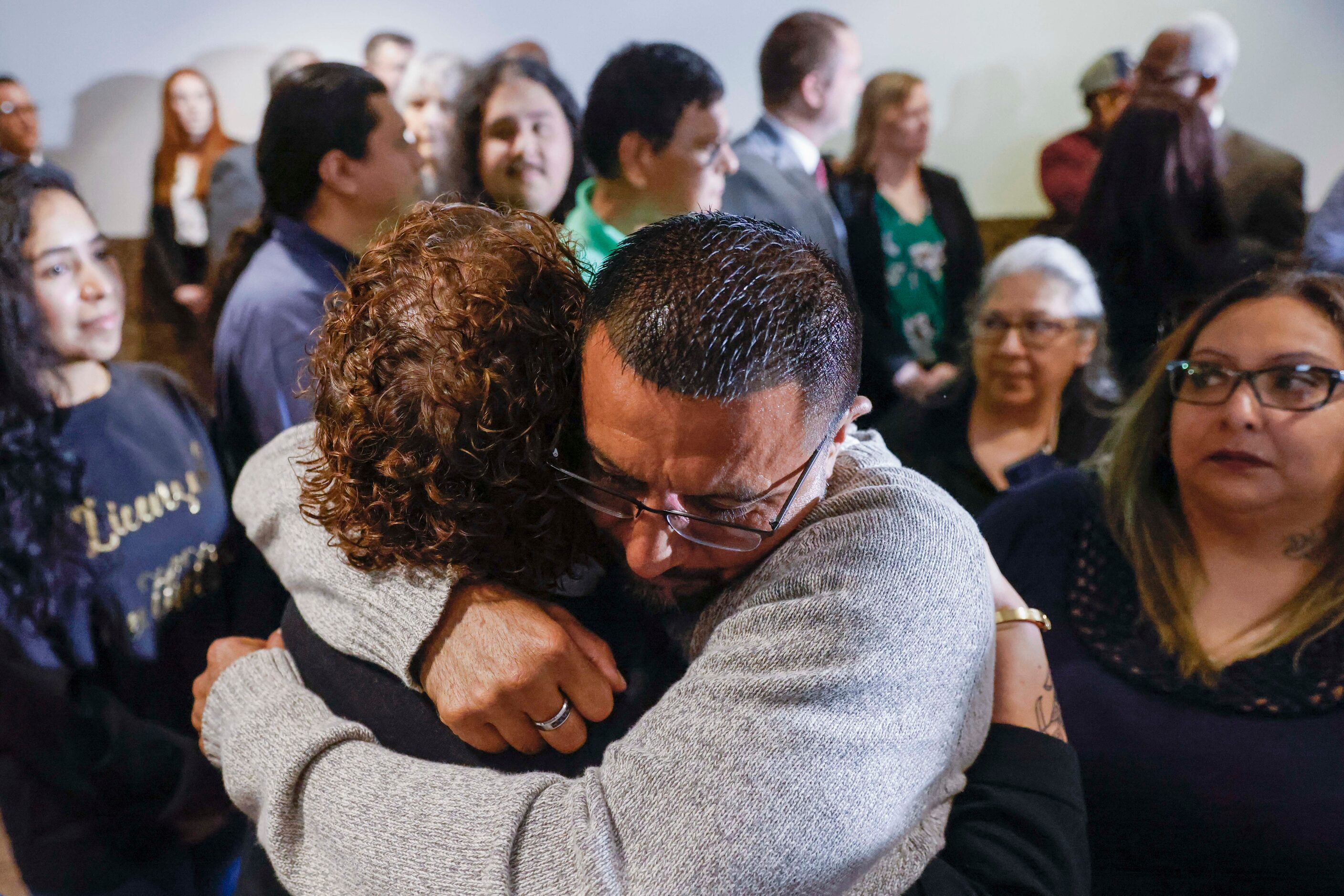 Surrounded by family members, Martin Santillan (center) embraces his friend Andrea Alvarado...