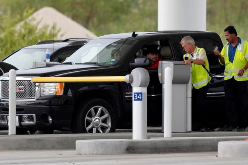
Workers at the South exit toll plaza help motorists at Dallas/Fort Worth International...