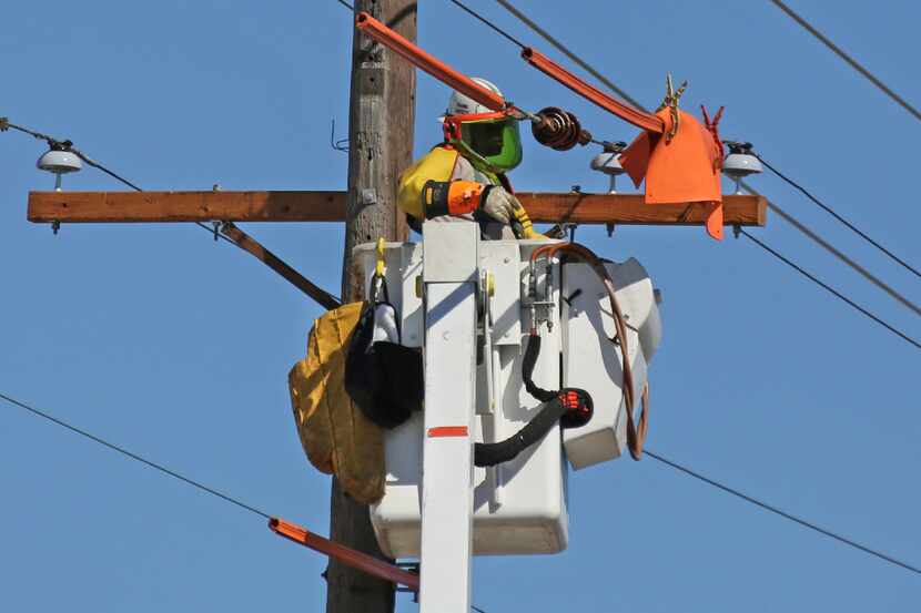 Oncor Electricity Delivery crews work along Canton Street near downtown Dallas on Friday,...