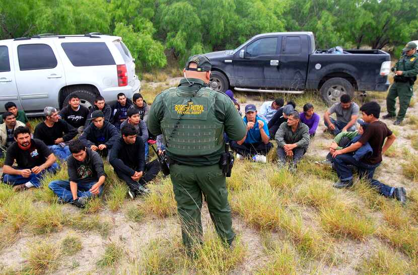 Immigrants suspected of being in the country illegally sit in a group after U.S. Border...
