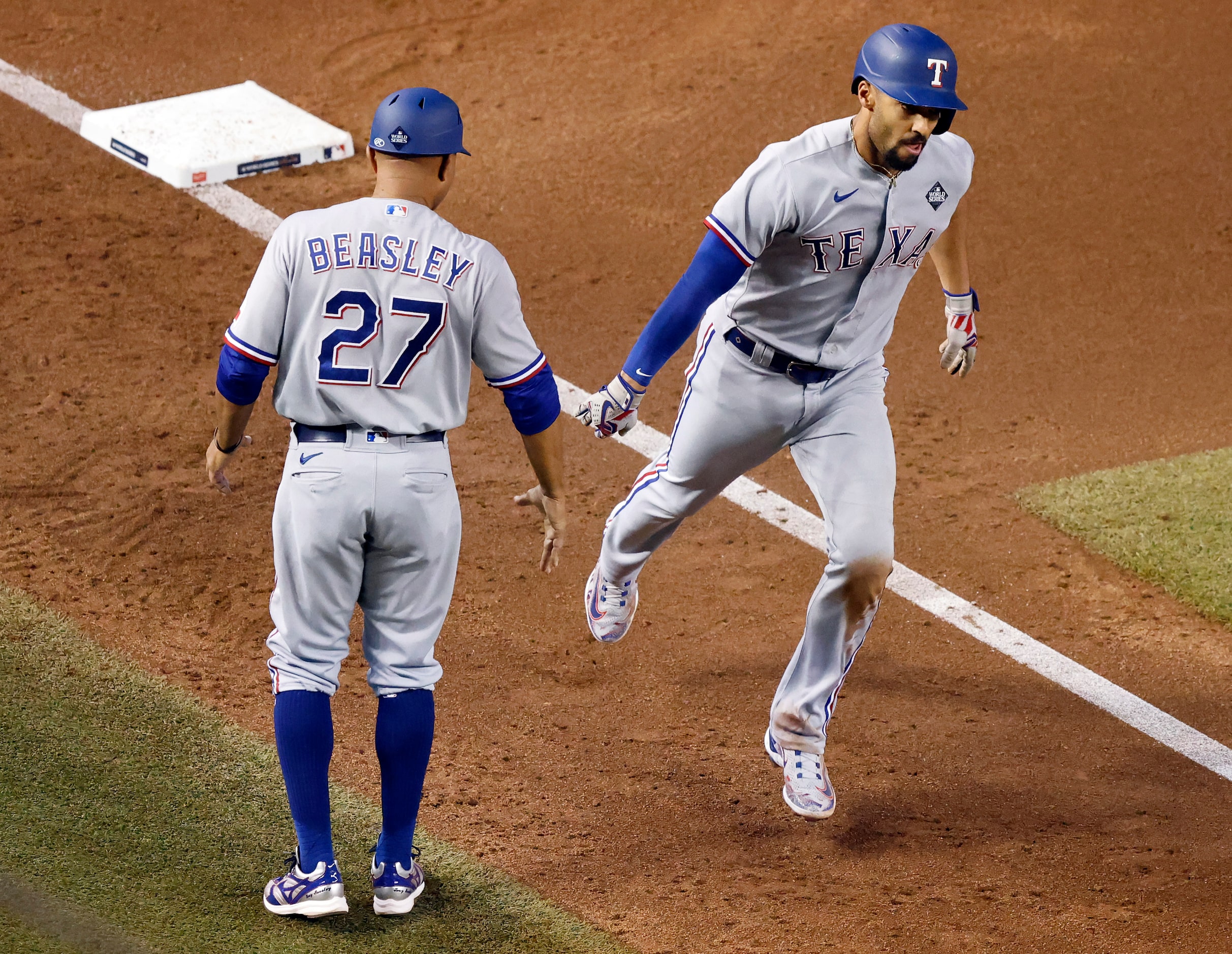 Texas Rangers second baseman Marcus Semien slaps hands with third base coach Tony Beasley...