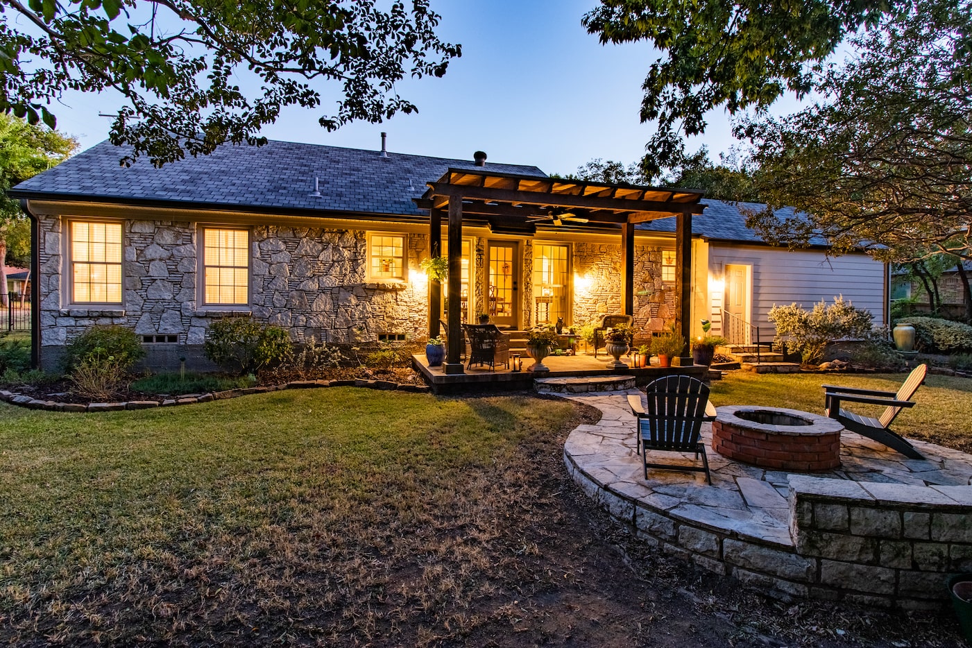 Outside find a pergola and a patio with a firepit, which is a cozy spot to enjoy the...