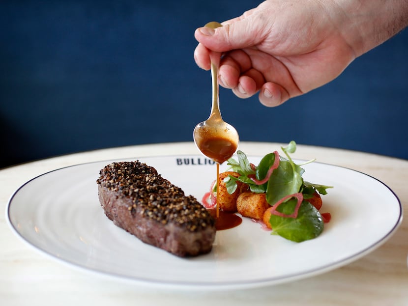 Chef Bruno Davaillon pours sauce on Bison Steak au Poivre.