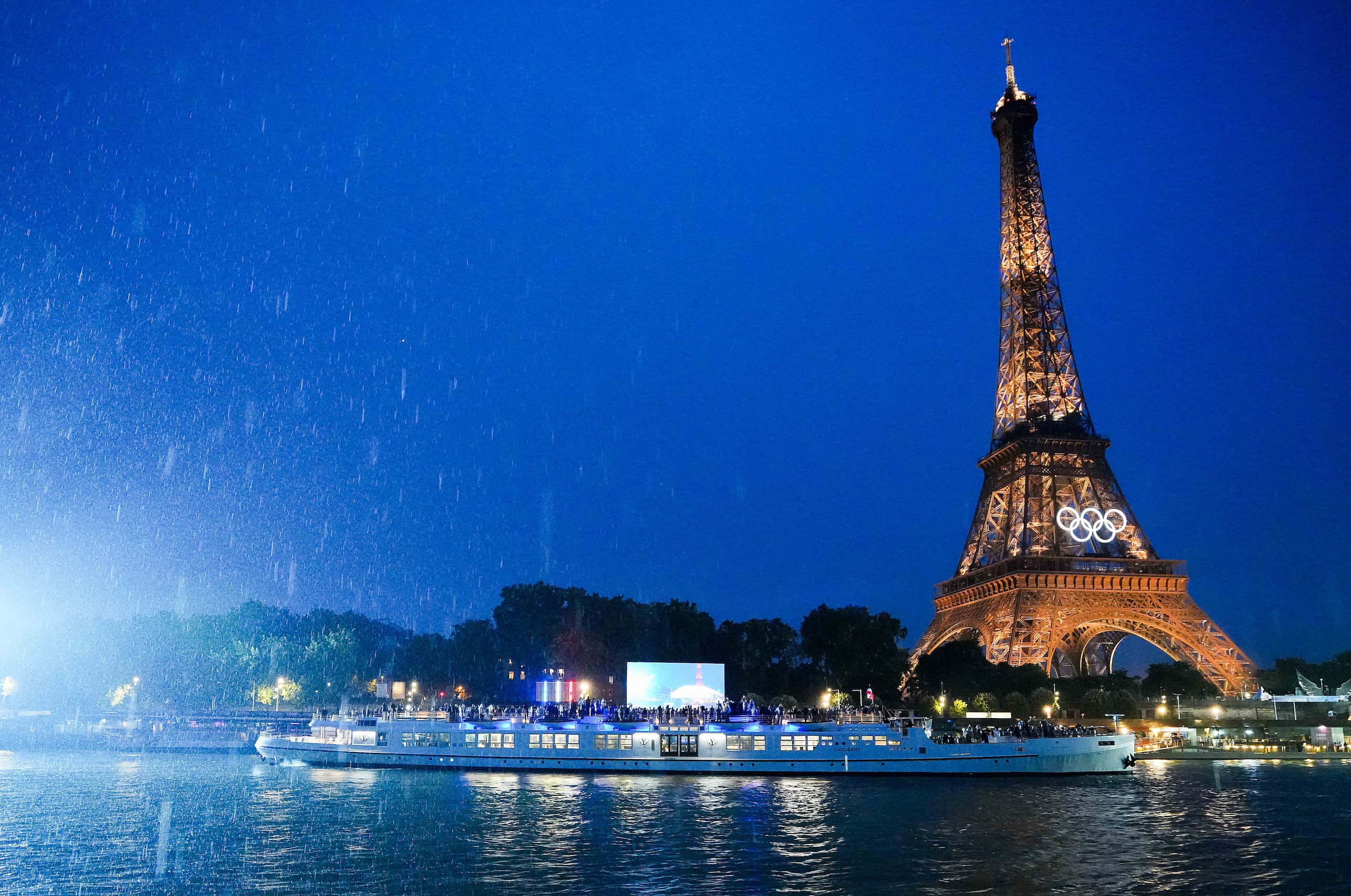 The boat carrying the host French delegation approaches the Eiffel Tower during opening...