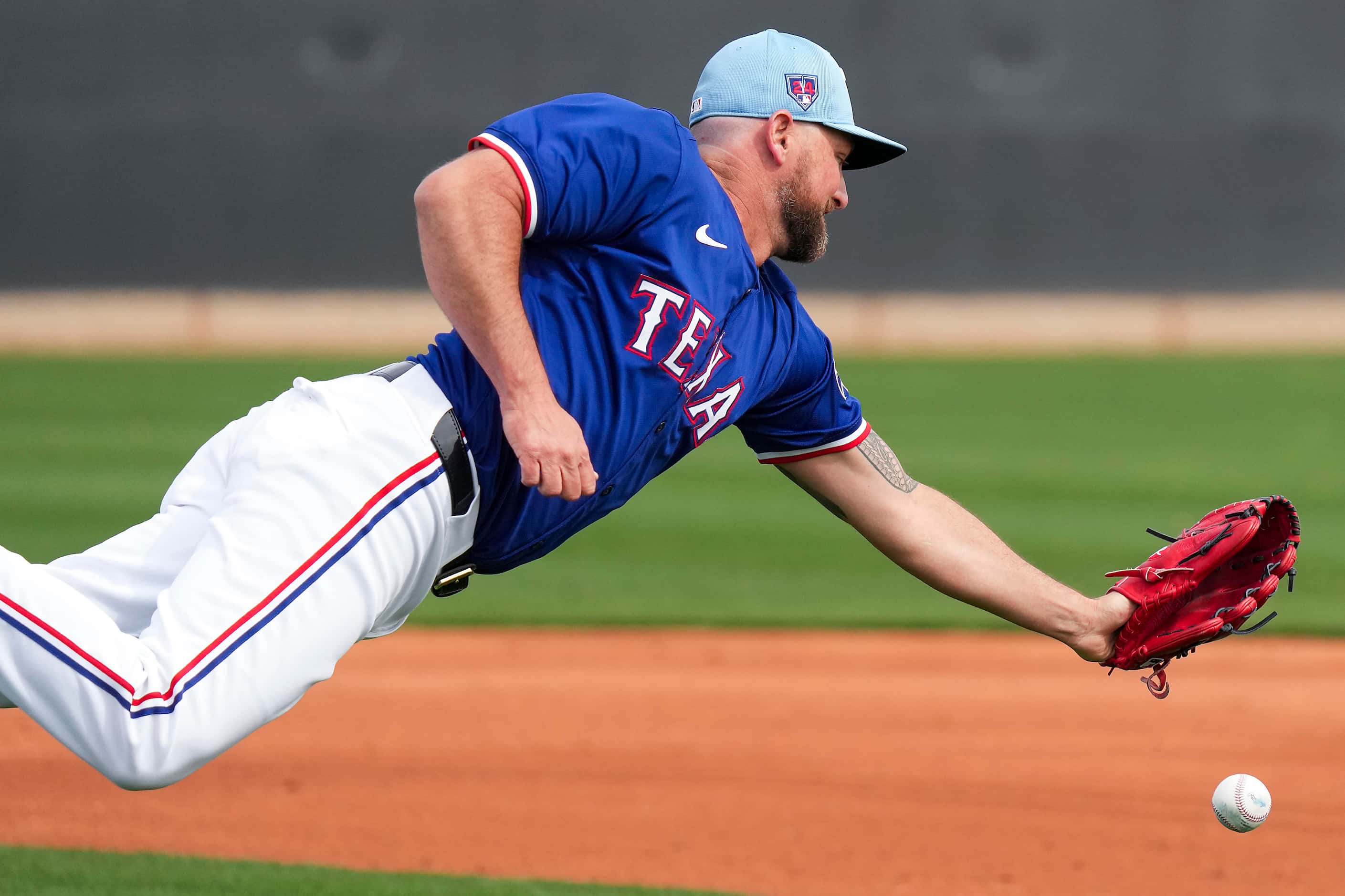 Texas Rangers pitcher Kirby Yates dives for a popup in a fielding drill during a spring...