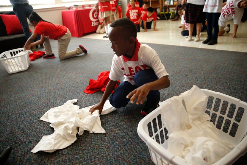 Jaylen Simpson, 8, gathers clothes during a laundry game at a celebration of Conn's HomePlus...