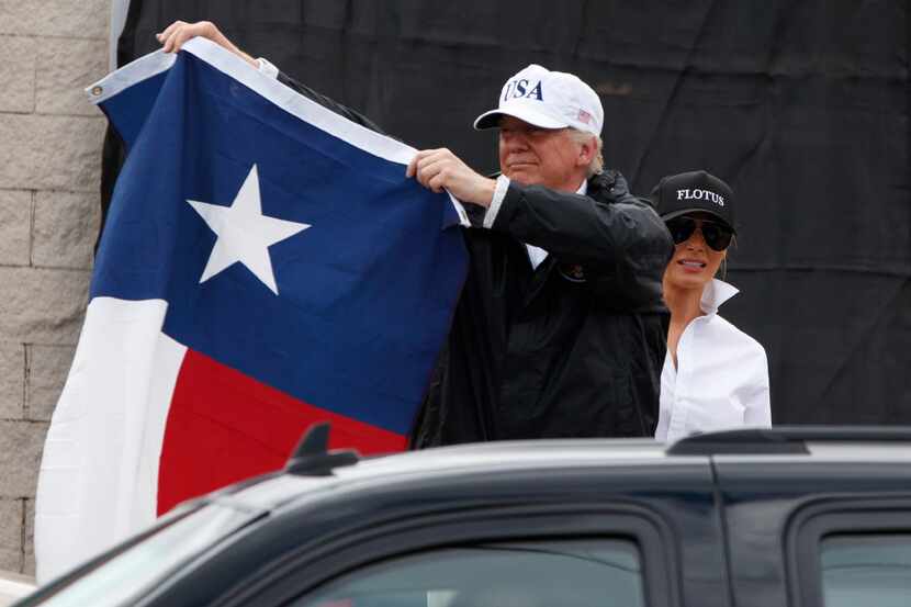 President Donald Trump, accompanied by first lady Melania Trump, holds up a Texas flag after...