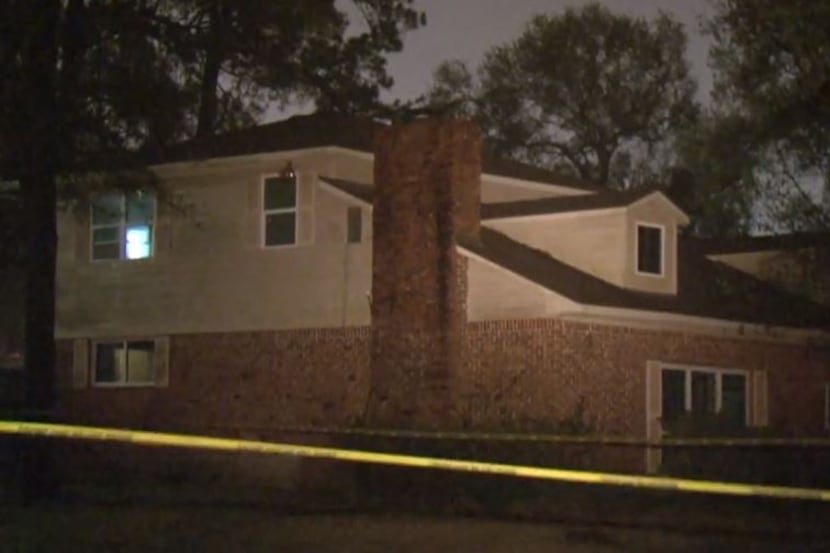 Police tape surrounds a home where someone sat on the roof and opened fire on a car full of...