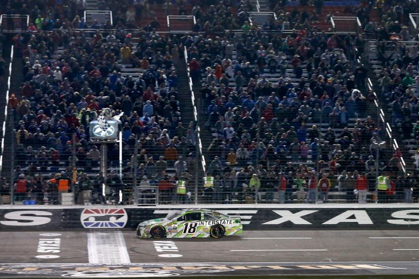 Kyle Busch (18) crosses the finish line to win the Duck Commander 500 race at Texas Motor...