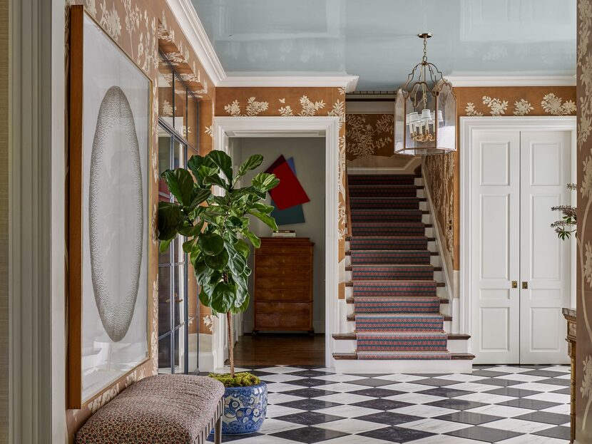 Hallway area with checkered floor and orange patterned wallpaper leading to stairs