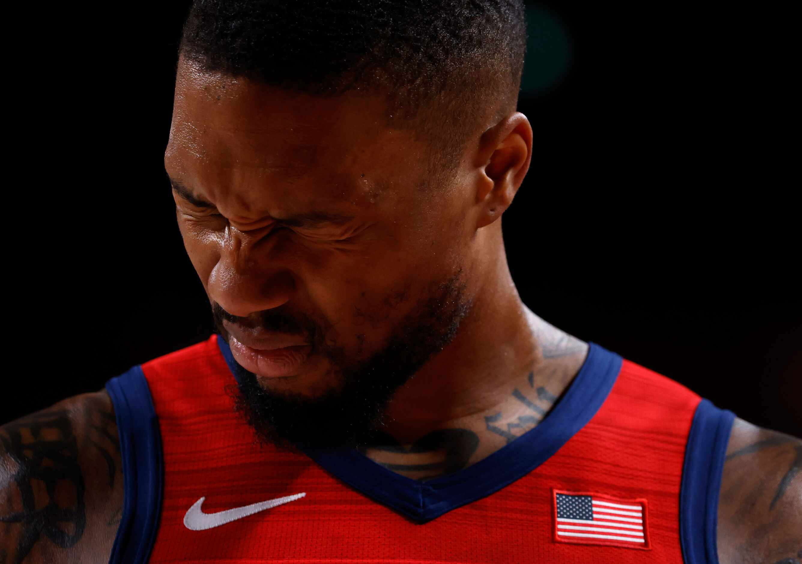 USA’s Damian Lillard (6) squints his eyes after getting hit in the face on a drive in a game...