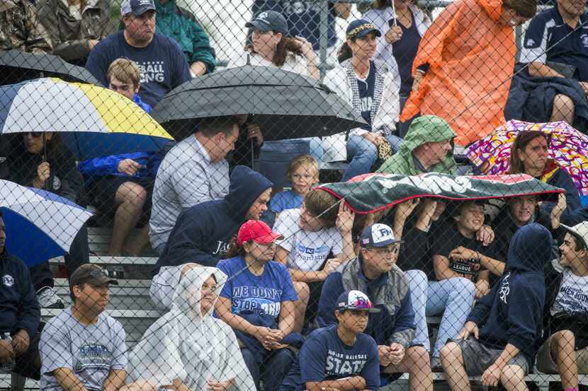 Flower Mound fans take cover from the rain during the first inning of a Class 6A, Region 1,...