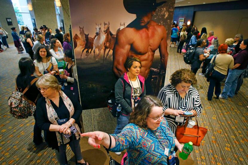 
Attendees at the Romantic Times Convention stand in front of a poster for “The Sons of...