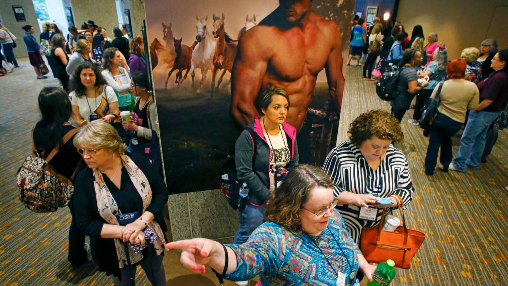 
Attendees at the Romantic Times Convention stand in front of a poster for “The Sons of...
