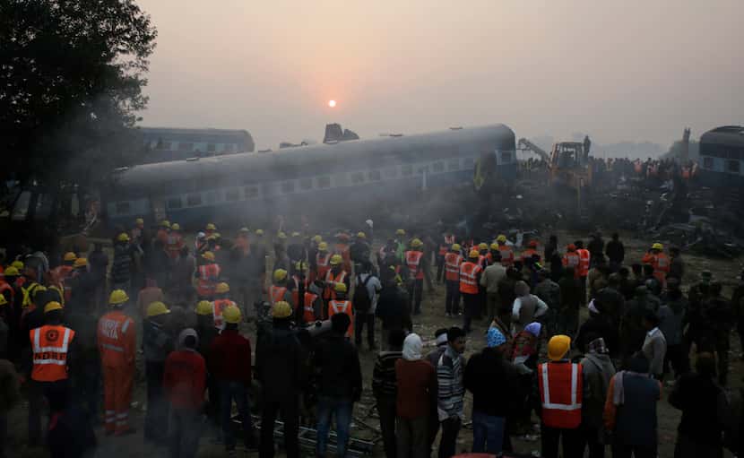 Rescuers work at the site after 14 coaches of an overnight passenger train rolled off the...