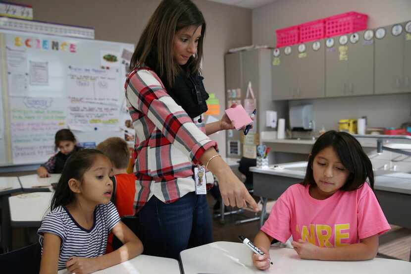 Teacher Grace Hanchey goes over a math problem with third-graders Sophia Arriaga (left) and...