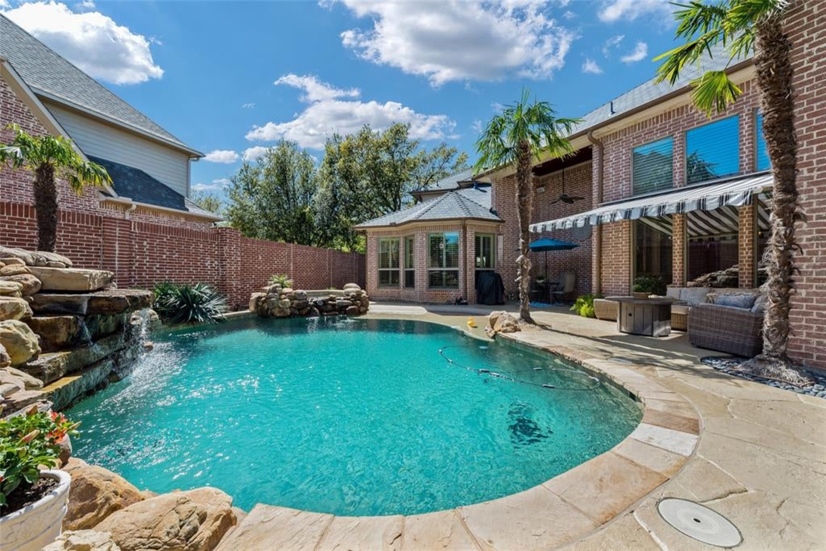 The oasis back yard offers an awning-covered patio and large pool with attached spa and rock...