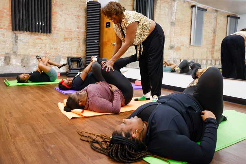 Instructor Cassandra Young  assists Tracina Porter of Dallas during a yoga class at...