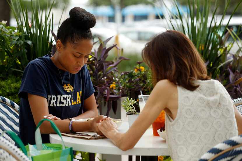 Cameasha Turner (left) prays with Cathey DeRouen, her third-grade teacher, before eating...