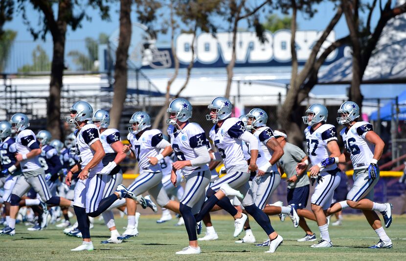 Players jog across a field during the afternoon practice at Dallas Cowboys training camp in...