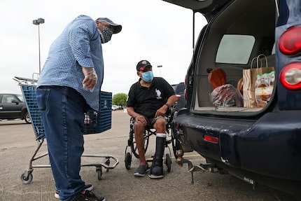 José Ángel Sánchez, de 60 años, recibe ayuda para su cargar su automóvil con comida en...