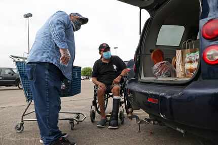 José Ángel Sánchez, de 60 años, recibe ayuda para su cargar su automóvil con comida en...