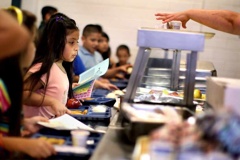 Alexandra Gonzalez, who will be in 2nd grade this fall, waits in line for a free lunch with...