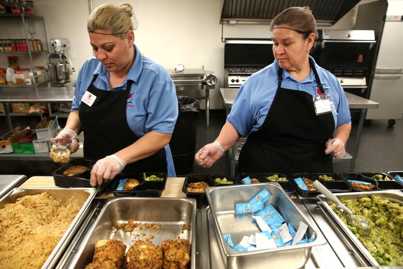 Food service staffers Maria Colesio (left) and Sandra Orozco prepare meals at Meals on...