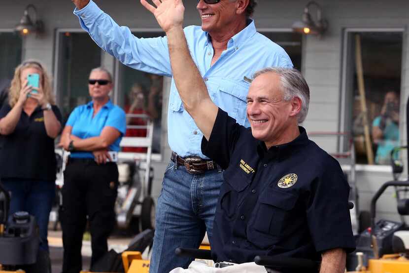 George Strait (left) and Texas Gov. Greg Abbott wave to the crowd in Rockport during a visit...