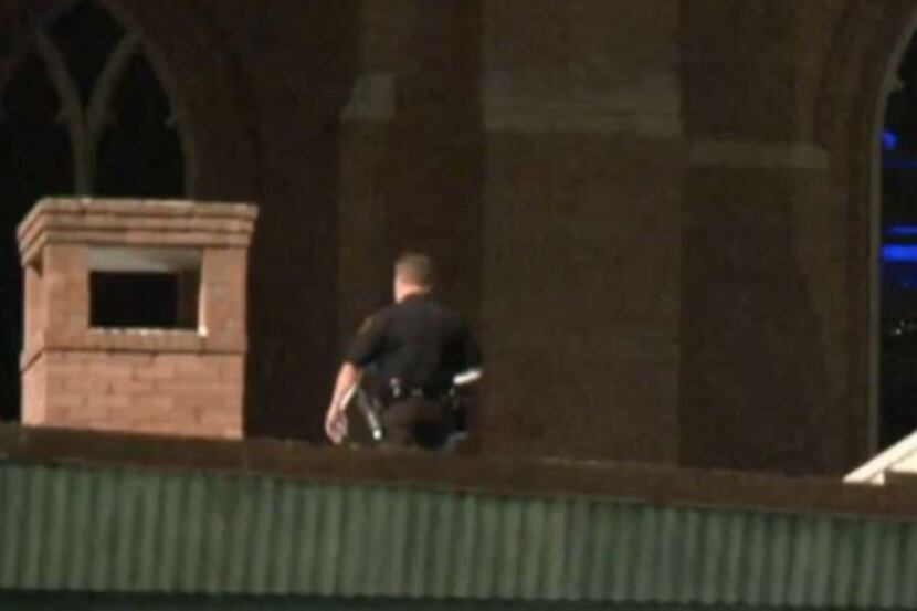 A Houston police officer scans the roof at St. Martin's Episcopal Church, looking for a man...
